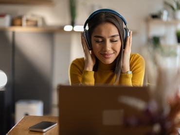 Beautiful young woman listening music on headphones while taking a break from work in home office