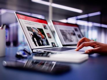 Laptopon híreket olvas, egy női kéz görget