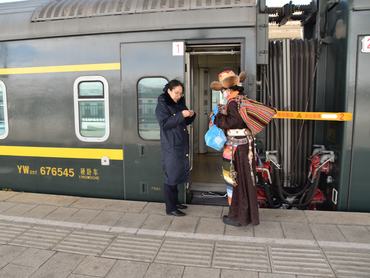 Egy kalauz ellenőrzi egy teljes hagyományos tibeti ruhát viselő nő jegyét a világ legmagasabban fekvő vasútállomásán, Tanggula állomáson, magasan a Tibeti-fennsíkon