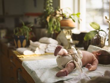 Full length of newborn baby wearing reusable diaper while lying down on table
