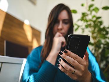 nő aggodalmasan nézi a telefon kijelzőjét