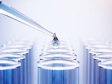 Folyadék átöntése üvegpipettából kémcsőbe laboratóriumban.