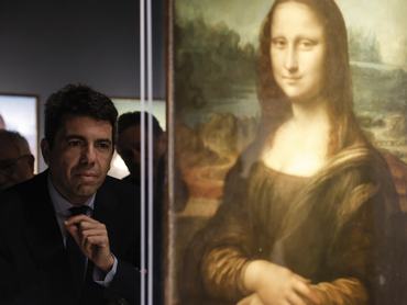 Carlos Mazón egy Leonardo da Vinci-kiállításon áll a Mona Lisa portréja mellett, a háttérben múzeumi installációval és kiállítási elemekkel.