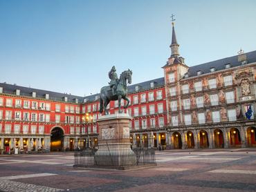 Picture shows a view of the Equestrian bronze statue of Philip III, located in the famous Plaza Mayor of Madrid, in the Los Austrias district, in the heart of the historic district of the city. The square is one of the most visited site in Madrid and a popular place of gathering. It was designed in 1619 by Juan Gómez de Mora in the Herrerian style. The statue was built by the Italian artist John of Bologna but was completed by his disciple Pietro Tacca in 1616. The facade of the Casa de la Panadería, a XVIth baroque style building decorated with paintings, former bakery of the medieval town, can be seen in the right side. The building houses municipal services nowadays. Red apartment buildings with arcades are visible on the left side. The photography was taken at dawn, during the blue hour, when the square was illuminated, calm and empty.