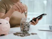 An Asian woman plans to divide her money into coins and a piggy bank, symbolizing budgeting, financial planning, saving, and smart money management.