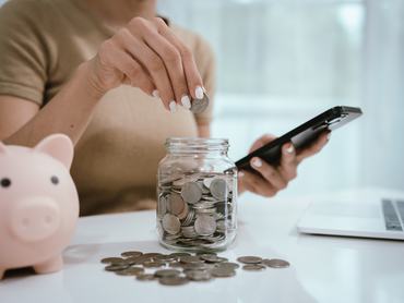 An Asian woman plans to divide her money into coins and a piggy bank, symbolizing budgeting, financial planning, saving, and smart money management.