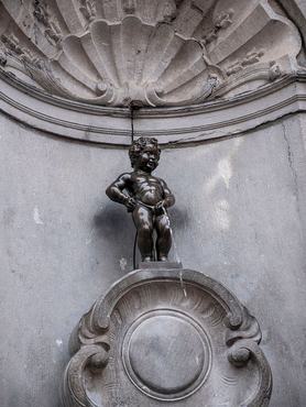 BRÜSSZEL, BELGIUM – 2025.01.17.: Víz folyik a pisilő kisfiút ábrázoló bronzszoborból, a Manneken Pisből („pisilő kisember”) Brüsszelben, Belgiumban.