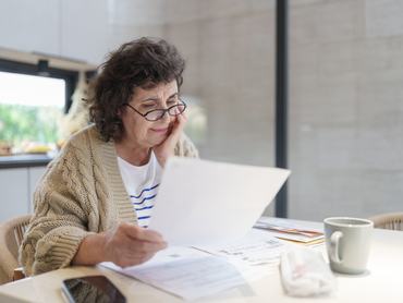 Stressed and Worried Senior Woman Calculating Domestic Expenses, Sitting at Dining Table in the kitchen, People, Accounting, Finances, Family Budget and Financial Issues Concept.