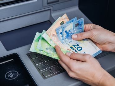 Egy kézpár eurót számol az ATM automata felett