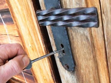 Egy férfi kéz nyitja egy fa ajtó zárját