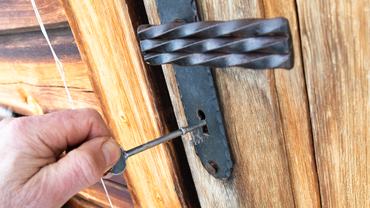 Egy férfi kéz nyitja egy fa ajtó zárját