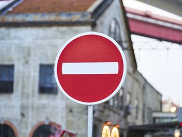 Red no entry traffic sign with a white bar, standing on a city street in Lisbon, symbolizing restriction and prohibition