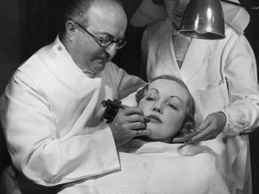 1937: J. C. Bell plasztikai sebész munka közben egy vendég arcán szépségszalonjában. (Fotó: Fox Photos/Getty Images)