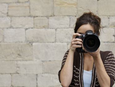 Portrait of a female photographer looking through the viewfinder of a Nikon D3 DSLR while on location in Bath, England, taken on August 14, 2013. (Photo by Olly Curtis/Future via Getty Images)