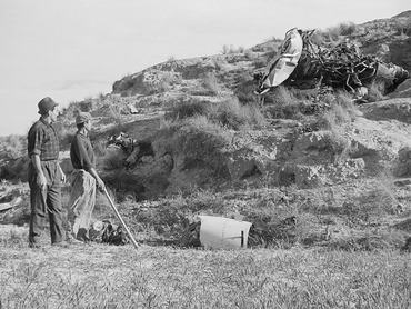 (Original Caption) Spanish workmen look at wreckage scattered over a hillside as they assist in the search for an atomic weapon missing in the crash of an American nuclear bomber here. American authorities have stressed there is no danger of explosion or radiation contamination in the area where a B52 bomber crashed Jan. 17th after colliding with a tanker plane. All but one of the "several" nuclear devices aboard the bomber have been recovered.