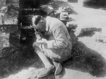 (Original Caption) C. Leonard Woolley, director of the joint expedition of the British Museum and University Museum at Ur, of the Chaldees, the buried city of Abraham. Mr. Woolley is seen brushing earth away from 4000-year-old records in the temple of the Moon God. His discoveries have moved Babylonian history back more than 2000 years and revolutionized our knowledge of the cradle of the human race.