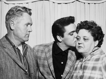 Elvis Presley énekes megcsókolja édesanyját, Gladyst, a hadseregbe való besorozása előestéjén. Bal oldalon édesapja, Vernon látható.
