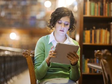 Young adult student using a computer tablet in an old library