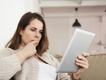 Nő tabletet néz, gondolkozik