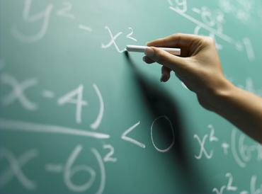 Matematikaórán egy tanuló krétával a táblára ír