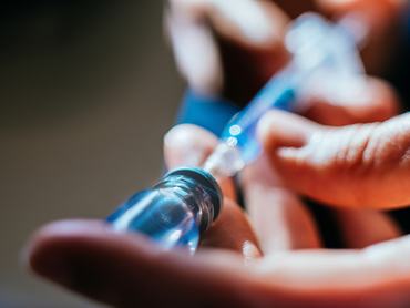 Női kéz injekciót szív fel közeli felvételen