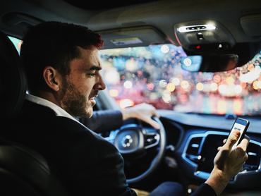 egy férfi használja a mobilját az autóban