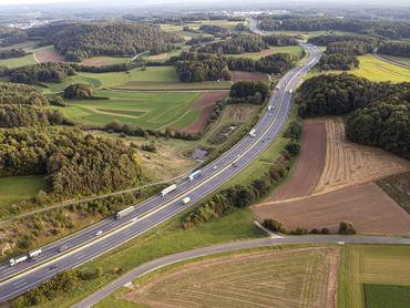 Légifelvétel egy autópályáról ahol személyautók és kamionok közlekednek
