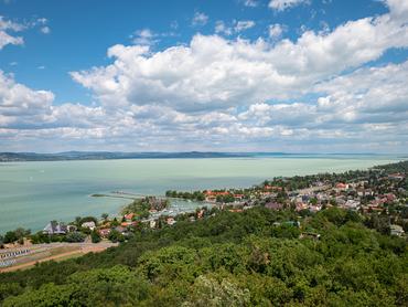 Kilátás egy dombról a Balaton-parti Fonyód kikötőjére és falujára egy napsütéses nyári napon.