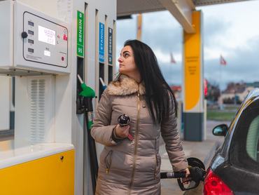 Egy fiatal nő megtankolja az autóját egy benzinkútnál. Az árat nézi.