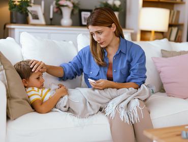 Egy hangulatos nappaliban egy odaadó anya éppen megméri beteg gyermeke lázát, vigasztalja őt és gondoskodik róla, miközben a kisfiú egy fehér kanapén pihen.