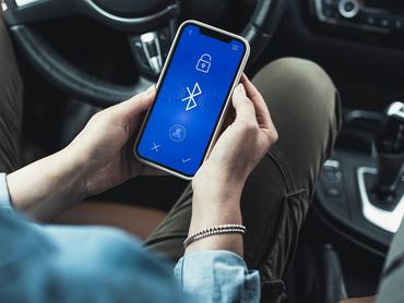 Bluetooth-funkció egy autóban ülő férfi kezében lévő okostelefon kijelzőjén