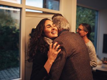 A nagyszülők fogadják a családot a bejárati ajtónál, a nagypapa megöleli a lányát