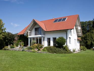 Emeletes családi ház kerttel, zöld pázsittal és napelemmel a tetőn