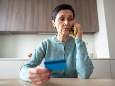 Egy ijedt, ideges nő telefonon átutal pénzt csalóknak.