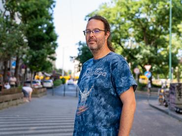 Cserhalmi Dániel író az utcán, kék pólóban