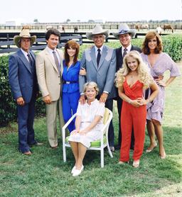 A „Dallas” című amerikai televíziós sorozat egyik promóciós fotója a szereplőgárdát ábrázolja a texasi Dallas külvárosában található Southfork-ranch területén, 1979-ben. Balról jobbra: az amerikai színészek Steve Kanaly (Ray Krebbs szerepében), Patrick Duffy (Bobby Ewing szerepében), Victoria Principal (Pamels Barnes Ewing szerepében),  (ülve), Barbara Bel Geddes (Eleanor Southworth „Miss Ellie” Ewing szerepében), Jim Davis (1909–1981) (John Ross „Jock” Ewing szerepében), Larry Hagman (John Ross „J.R.” Ewing, Jr. szerepében), Charlene Tilton (Lucy Ewing szerepében) (piros ruhában) és Linda Gray (Sue Ellen Ewing szerepében). (Fotó: CBS Photo Archive/Getty Images)