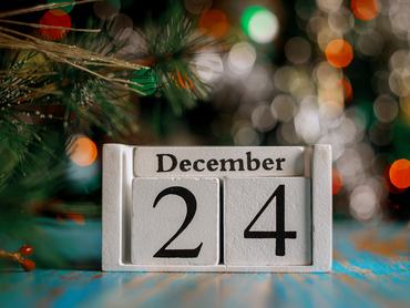 December 24. egy karácsonyfa-fényekkel díszített háttérrel ellátott fa naptárkockán. Karácsonyeste