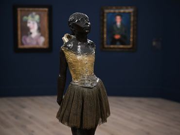 Edgar Degas szobra a 14 éves kis táncosnőről. A szobor szoknyát visel, a háttérben két homályos festmény