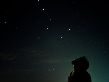 Egy férfi sziluettje a hatalmas csillagos égbolton, aki csendes ámulattal tekint fel a végtelen kozmoszra és az éjszaka nyugodt rejtélyére