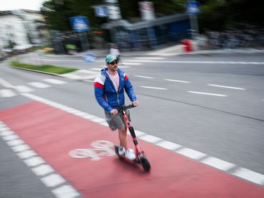 FELVÉTEL – 2024. július 28., Berlin: Egy férfi elektromos robogóval halad egy hamburgi kerékpárúton (hosszú záridővel készült felvétel). A német kormány új szabályokat tervez az elektromos robogókra vonatkozóan. Fotó: Christian Charisius/dpa (Fotó: Christian Charisius/picture alliance via Getty Images)