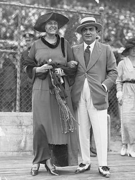 Enrico Caruso a feleségével, 1915 körül egy kerítés előtt áll, alkalmi öltözetben
