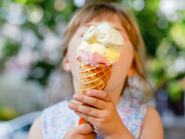 Egy kis óvodás kislány, aki egy napsütéses nyári napon gofri tölcsérben eszi a fagylaltját. Boldog kisgyerek, aki fagylaltot eszik. Édes finomság a forró, meleg nyári napokon. Erős fény, színes fagylalt.