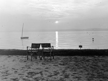 két egymás mellé tolt szék, a háttérben a Balaton naplementekor