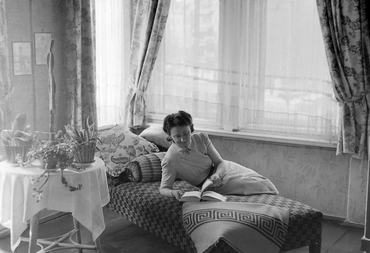 Egy nő könyvet olvasva fekszik az ágyon egy ablak előtt a lakásban 1942-ben.