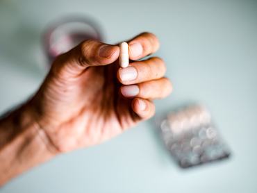 Közelkép egy felismerhetetlen férfiról, aki gyógyszert/kiegészítőt/gyógyhatású készítményt szed