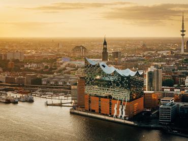 Légi felvétel Hamburgról alkonyatban, az Elbphilharmonie és a raktárépületek, valamint a kikötő