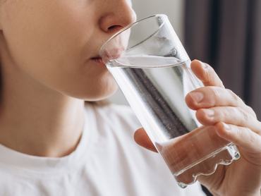 Közelkép oldalról egy egészséges, fiatal nőről, aki reggel tiszta, szénsavmentes vizet iszik. Kaukázusi hölgy, aki az egészséges életmódhoz tartozó napi szokásait, természetes szépségét, tökéletes bőrét és testápolását az „aqua balance” koncepció jegyében élvezi