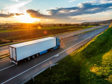 Egy kamion halad a vidéki autópályán a gyönyörű naplementében