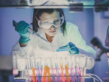 Egy nő a laboratóriumban végez vizsgálatot a mikroszkóp alatt
