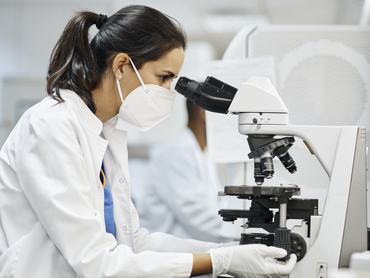 Egy nő belenéz a mikroszkópba a laboratóriumban